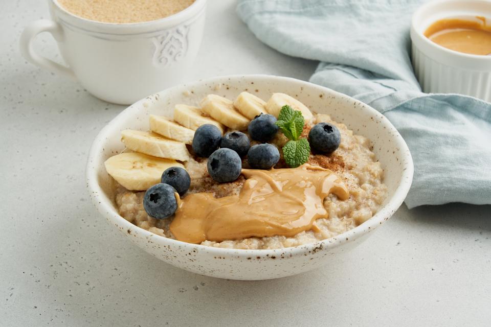 Oatmeal porridge. Traditional bunting breakfast served in ceramic bowl on gray background. Vegetarian and nutritious vitamin morning eating. Classic hot homemade dietary meal