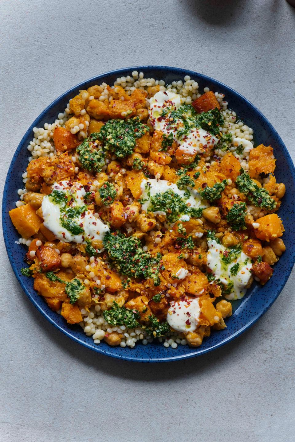 A bowl of grains, butternut squash, and herbs.