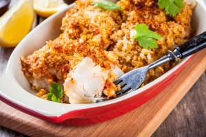 Baked codfish in breadcrumbs in gratin dish closeup with coriander