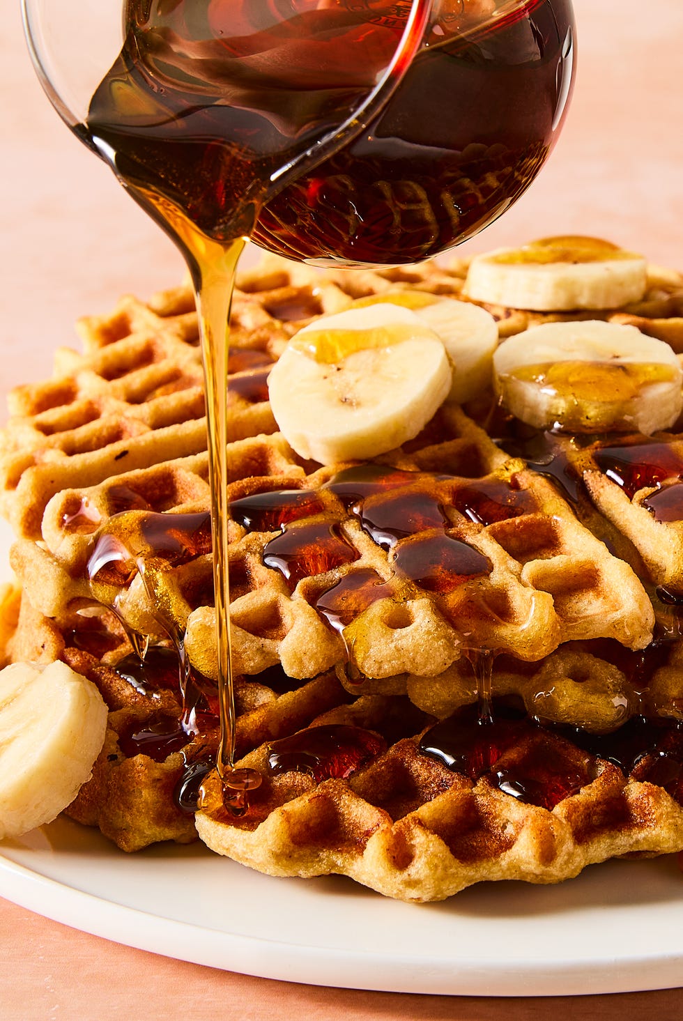 stacked waffles topped with banana slices and syrup