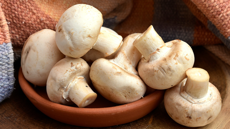 Raw button mushrooms in dish 