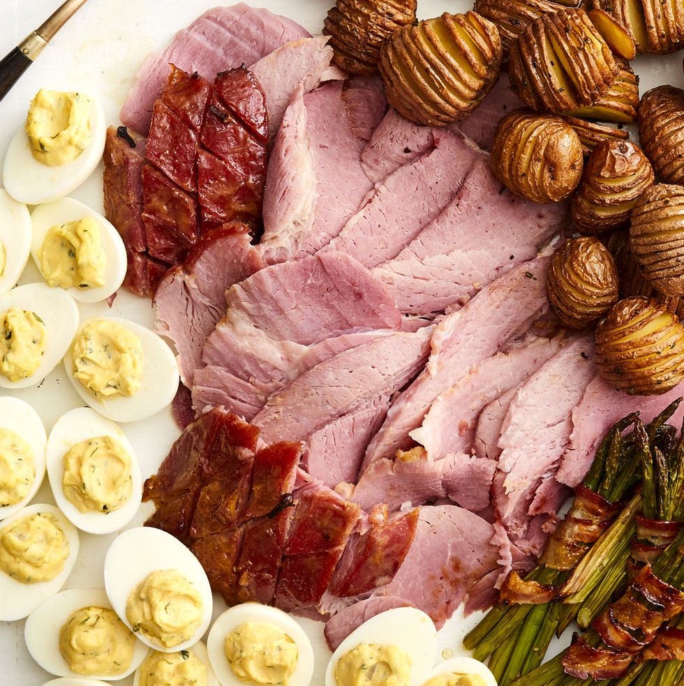 honey mustard glazed ham sliced on board with eggs, potatoes, and asparagus