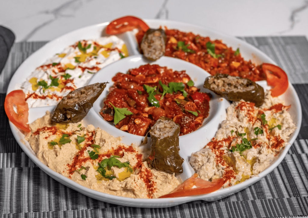 Plate of assorted meats and cooked veggies. The dish is divided into 4 quadrants. 
