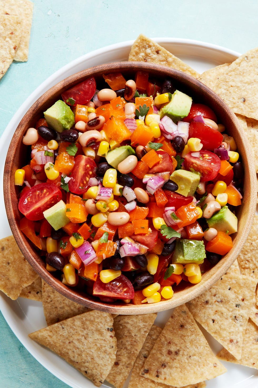 beans, tomatoes, red onion, and avocado in a bowl with chips