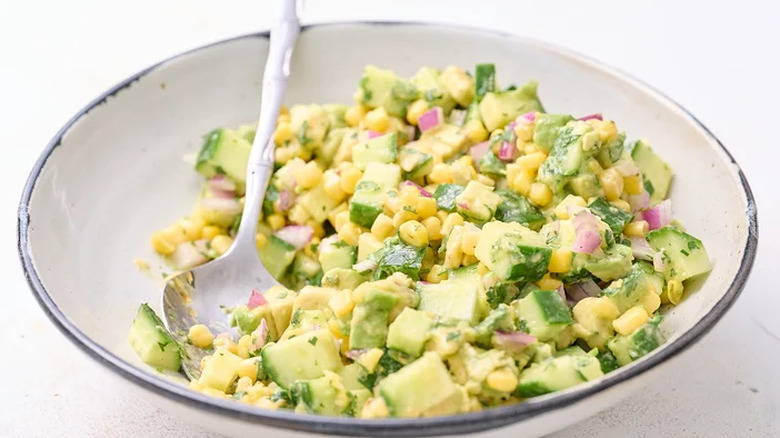Bowl of cucumber and avocado salsa with spoon