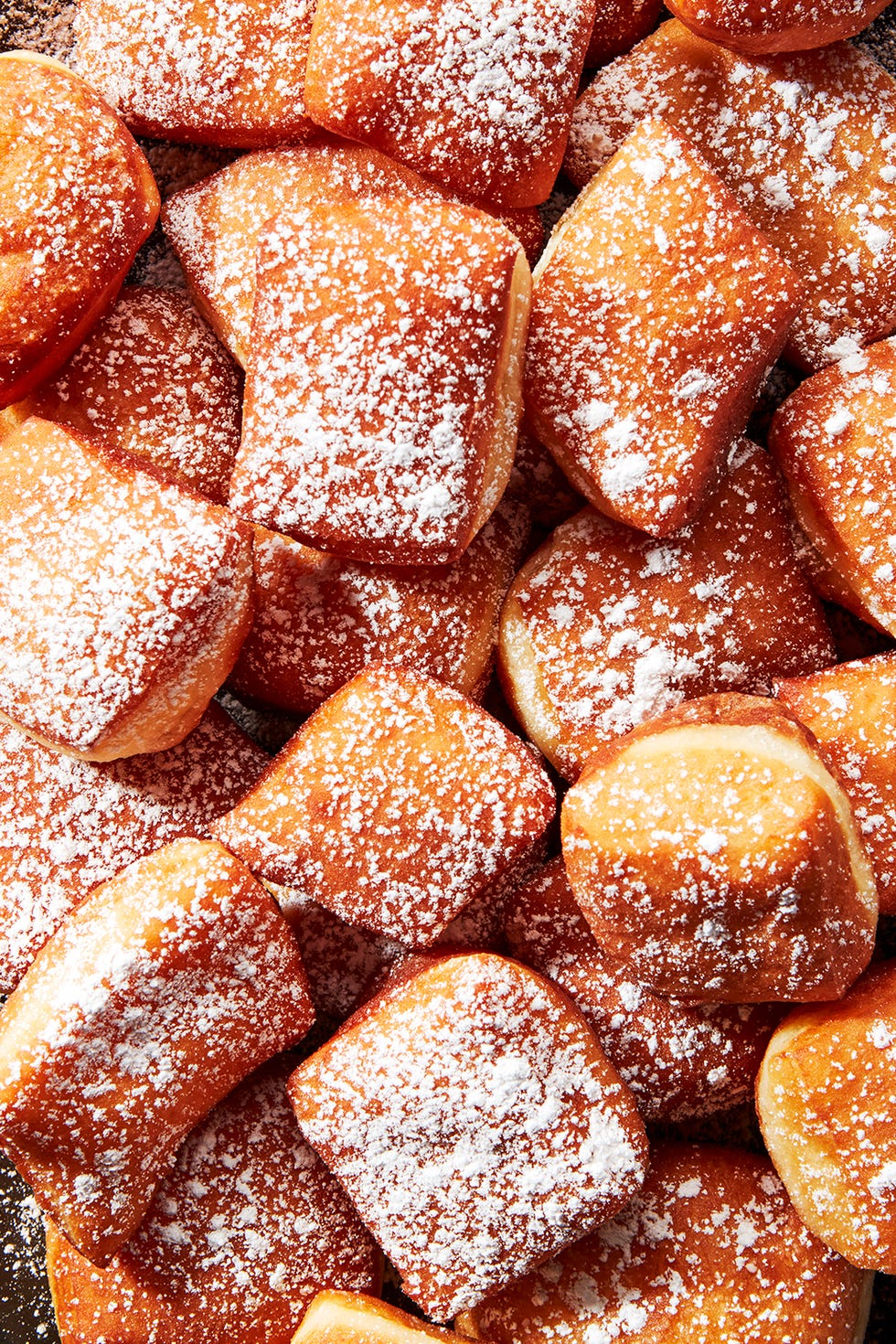 beignets on a platter dusted with powdered sugar