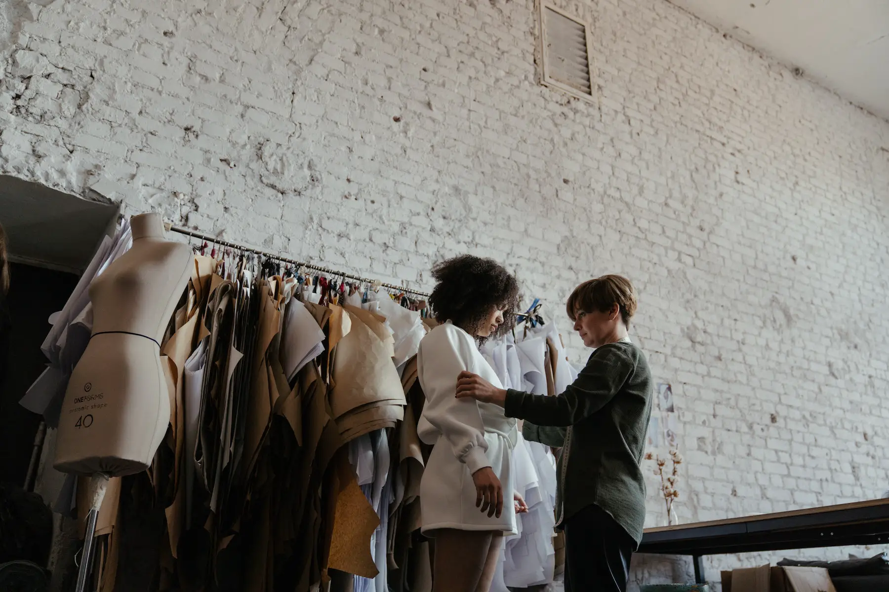 Seamstress fitting model with white sweater in studio