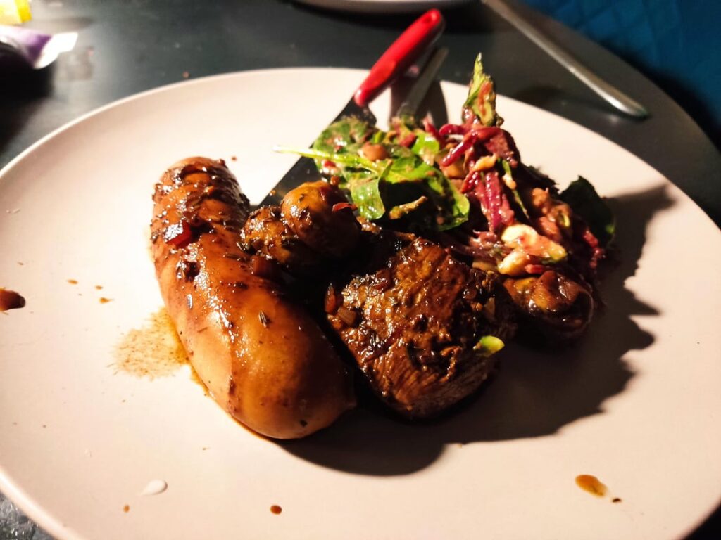 Marinated venison steak with mushrooms, bratwurst and a bistro salad