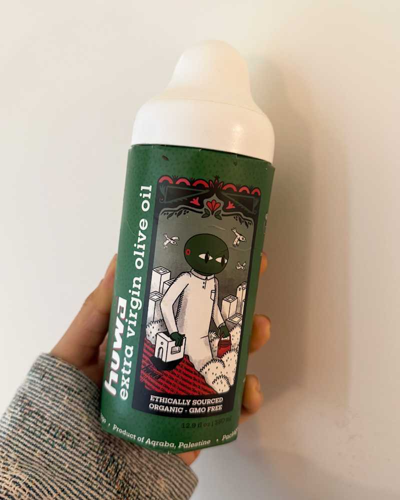 Someone holding a bottle of Huwa Palestinian Extra Virgin Olive Oil
