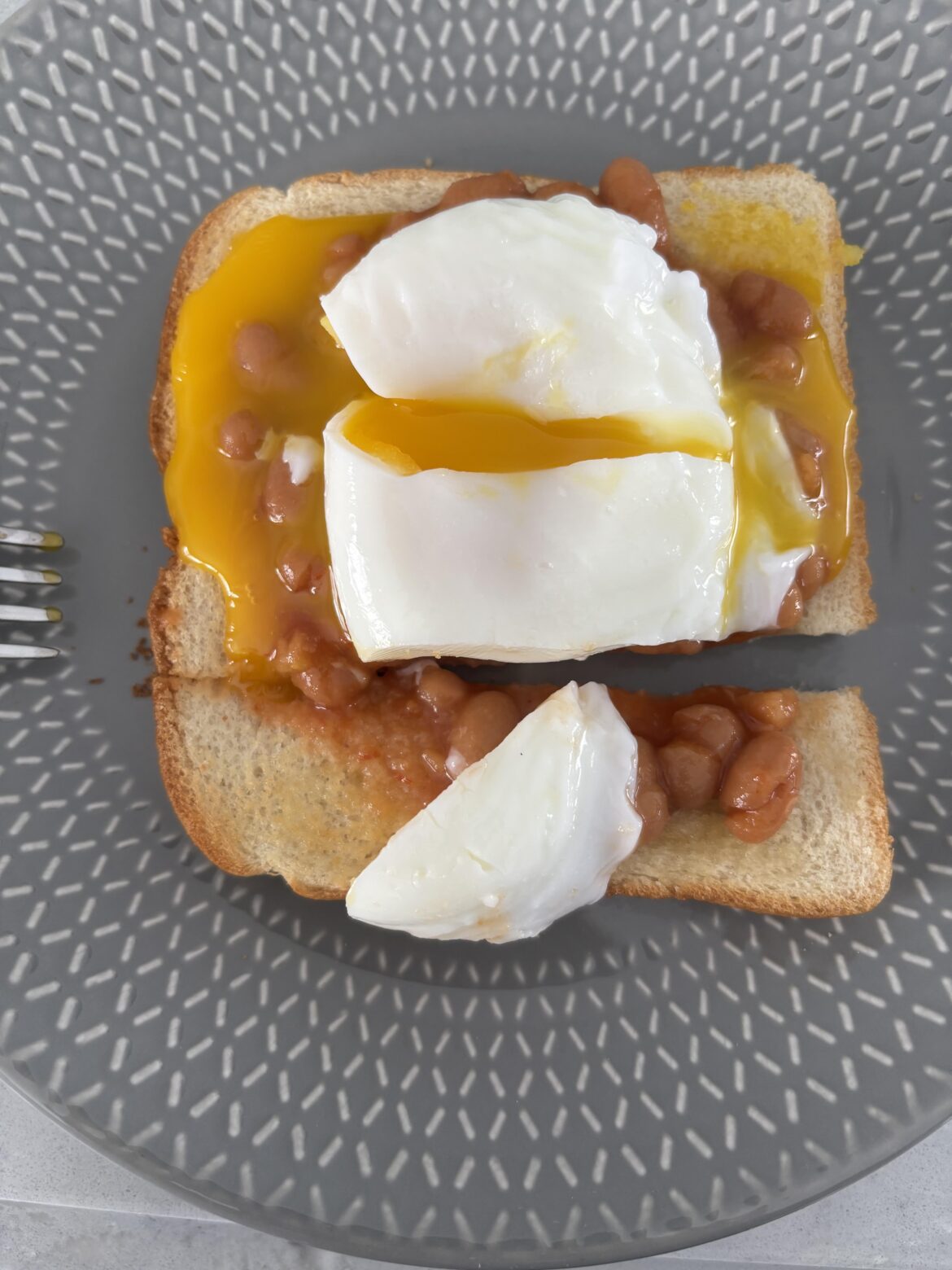 Beans on toast with a poached egg on it