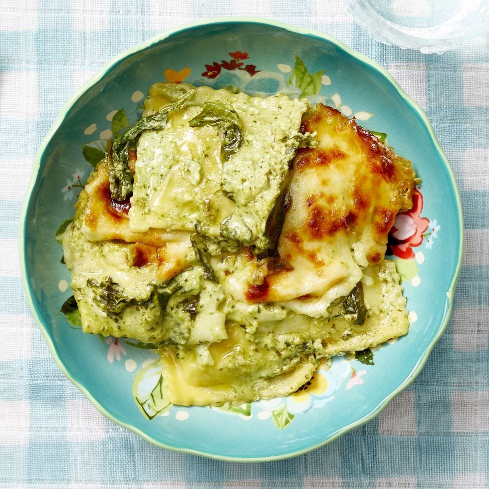 baked spinach ravioli with pesto cream sauce in blue bowl