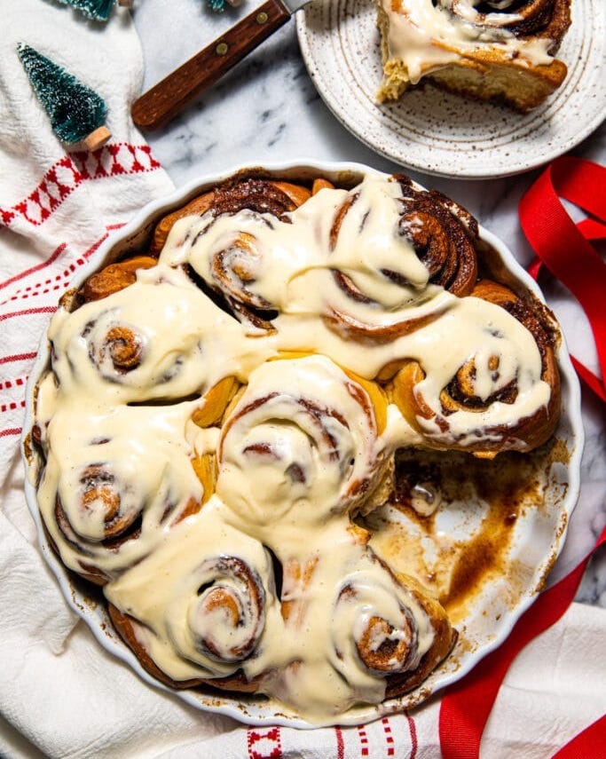 brown butter eggnog cinnamon rolls with red ribbon on side