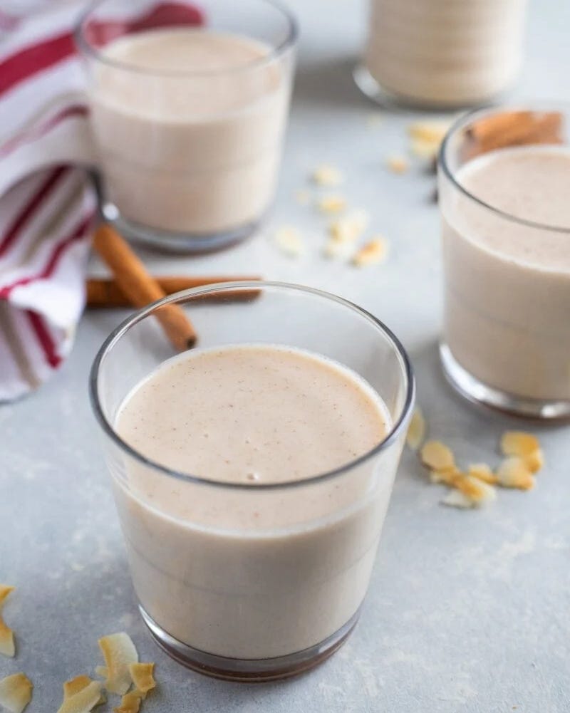 coquito in glass with coconut flakes on surface
