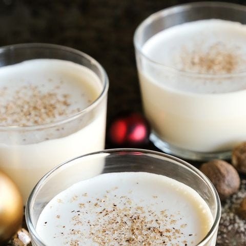 homemade eggnog with nutmeg in low glass with ornaments around