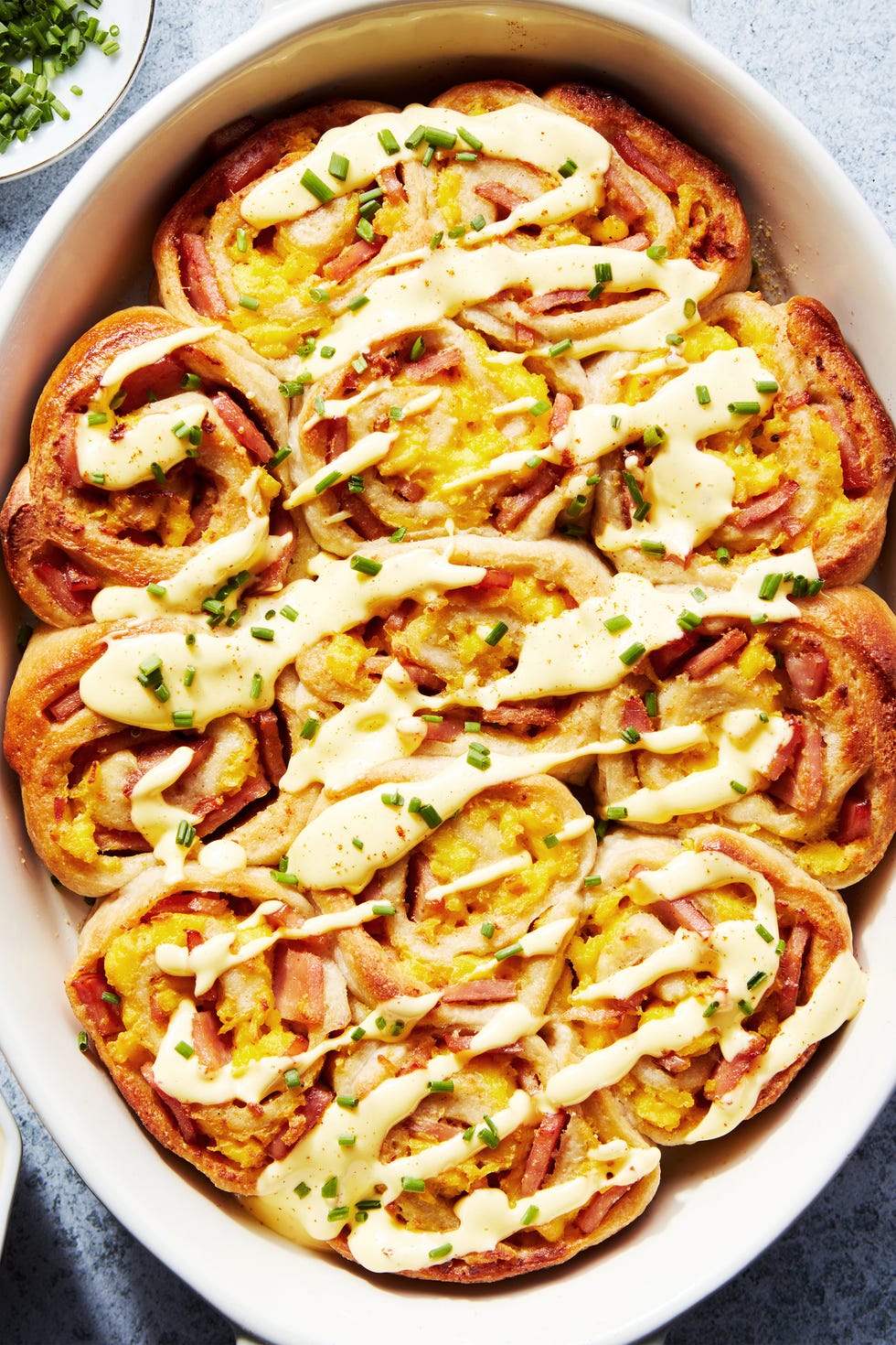 pinwheel style rolls baked in a casserole dish and topped with hollandaise