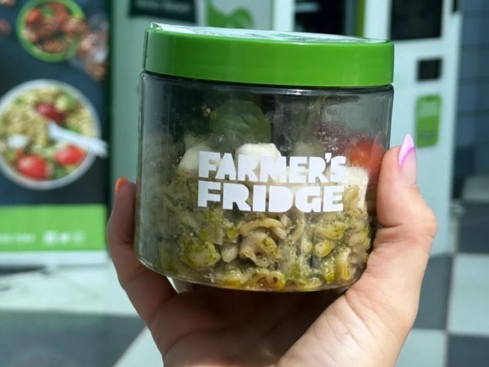 hand holding up pesto pasta from farmer's fridge vending machine