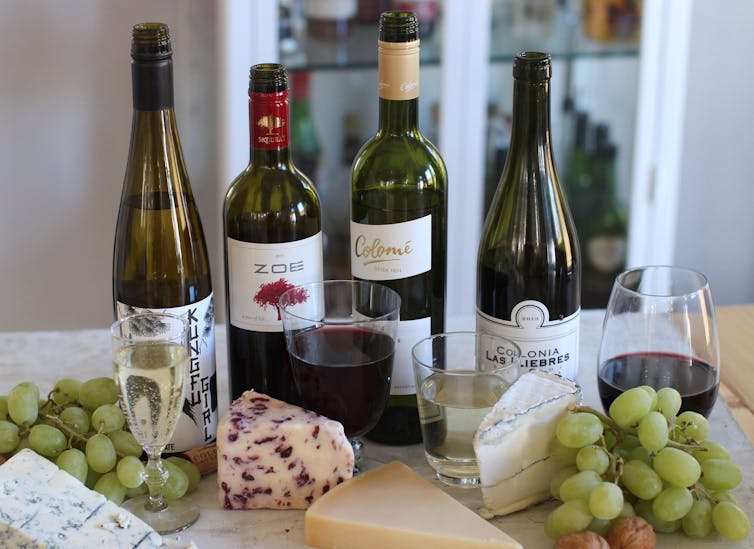 Four bottles of wine with cheese and grapes