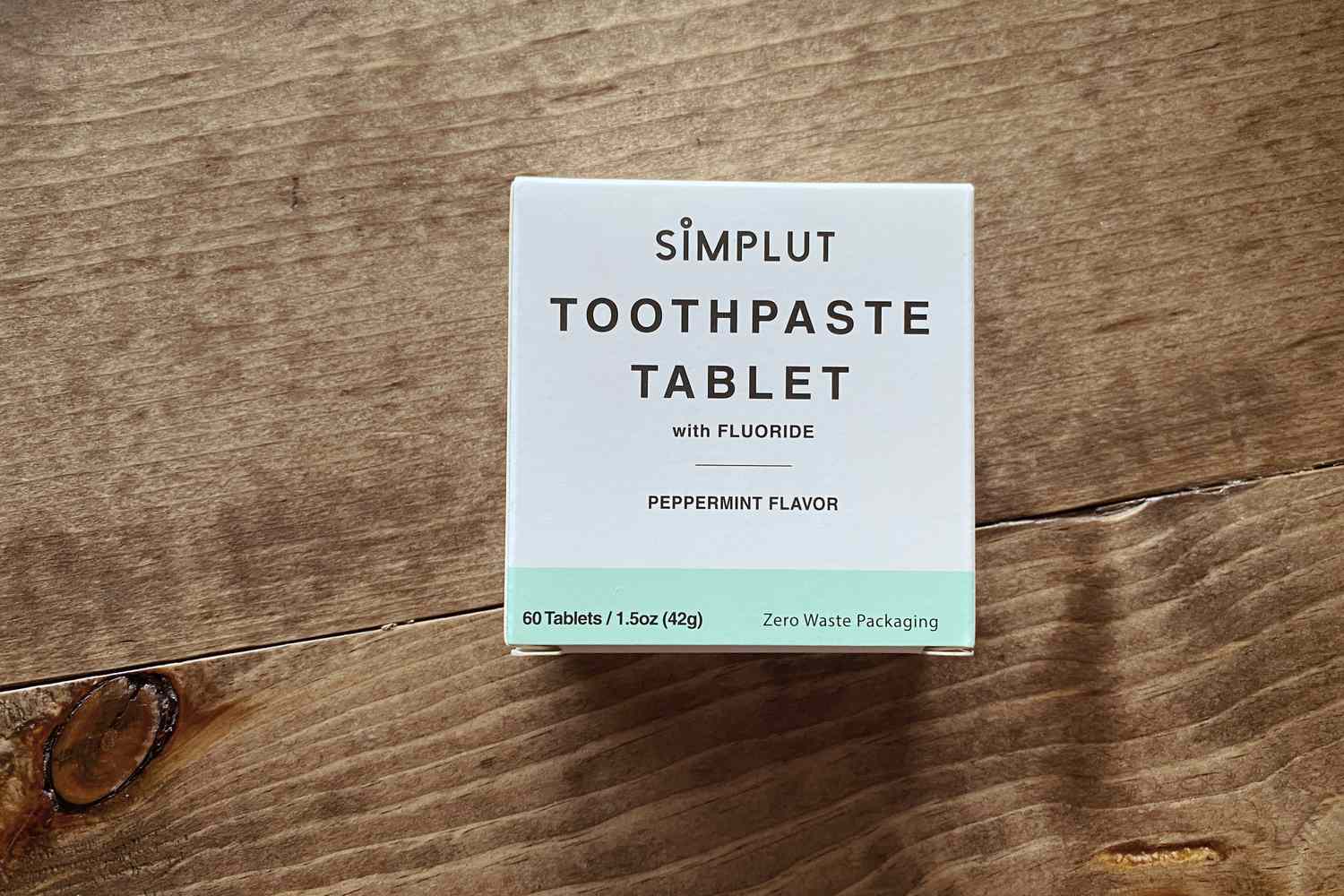 A box of Simplut Chewable Toothpaste Tablets with Fluoride on a wooden floor