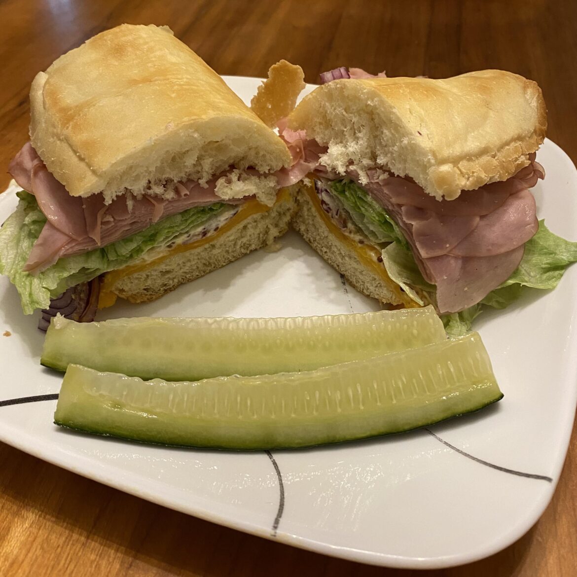 Quick lunch at home: thin-sliced Turkey, cheddar and crispy deli roll heated in the toaster over for a few minutes, then lettuce, red onion, Inglehoffer mustard and mayor. Homemade refrigerator pickles on the side.