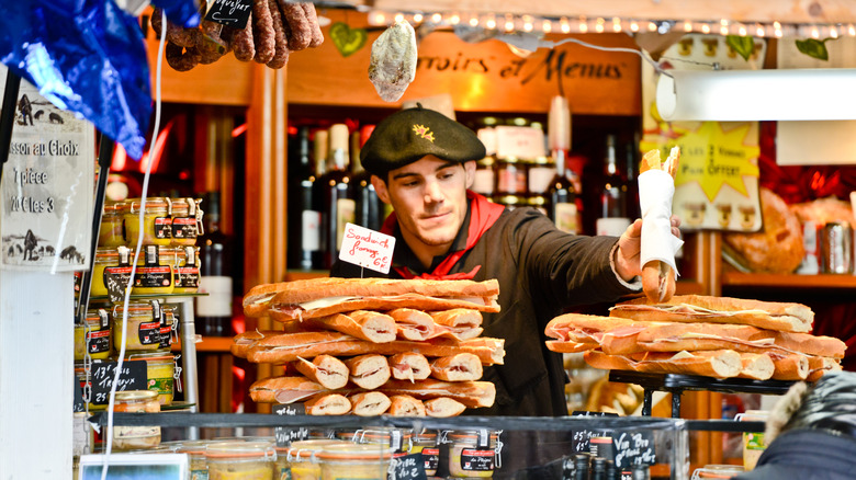 Employee handing baguette sandwich to a customer