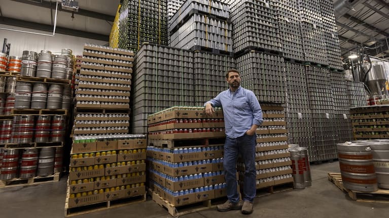 Jeff Ware, president of Resurgence Brewing Company, poses for a portrait near a stockpile of aluminum cans, which are sourced from Canada.