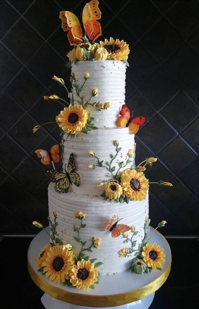 A sunflower and butterfly wedding cake that we created 🦋🌻