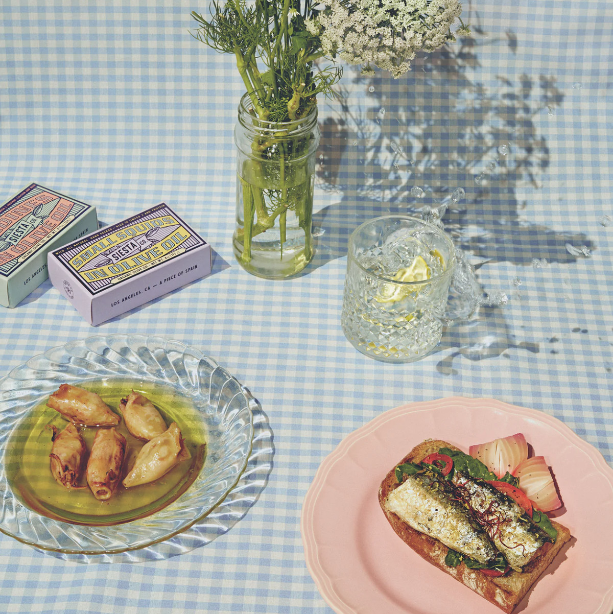 A decorated table with tinned fish with olive oil and toast.