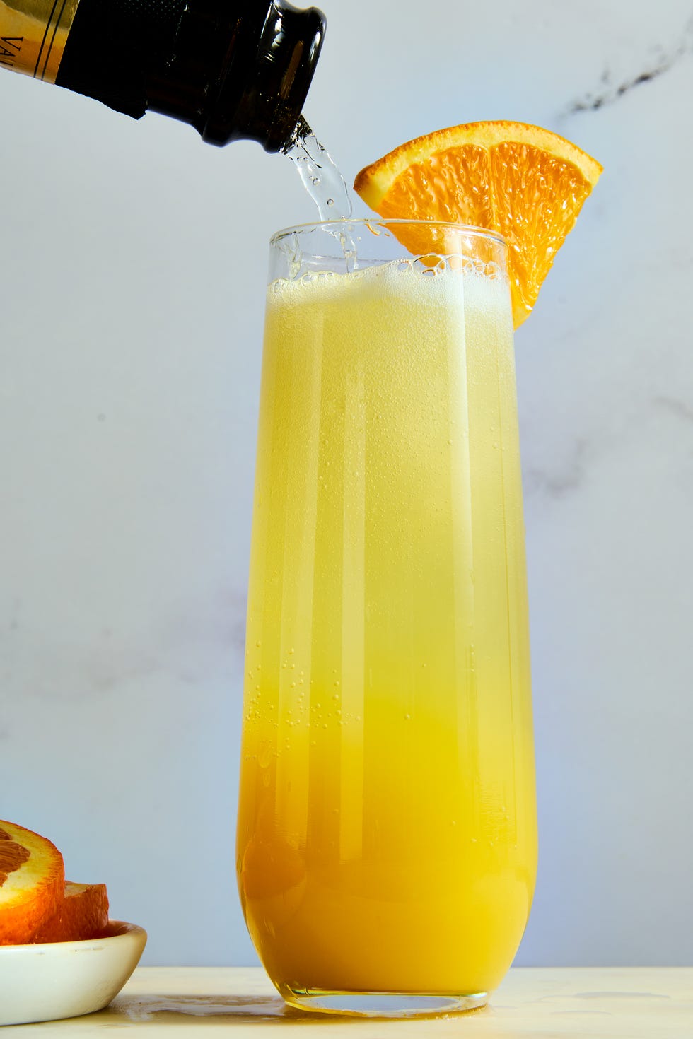 orange juice and champagne in a flute garnished with an orange wedge