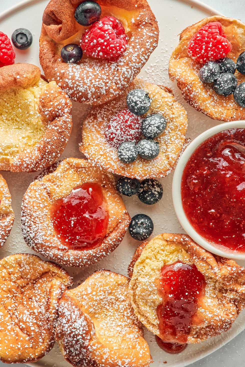 mini dutch baby pancakes with berries jam and confectioners sugar