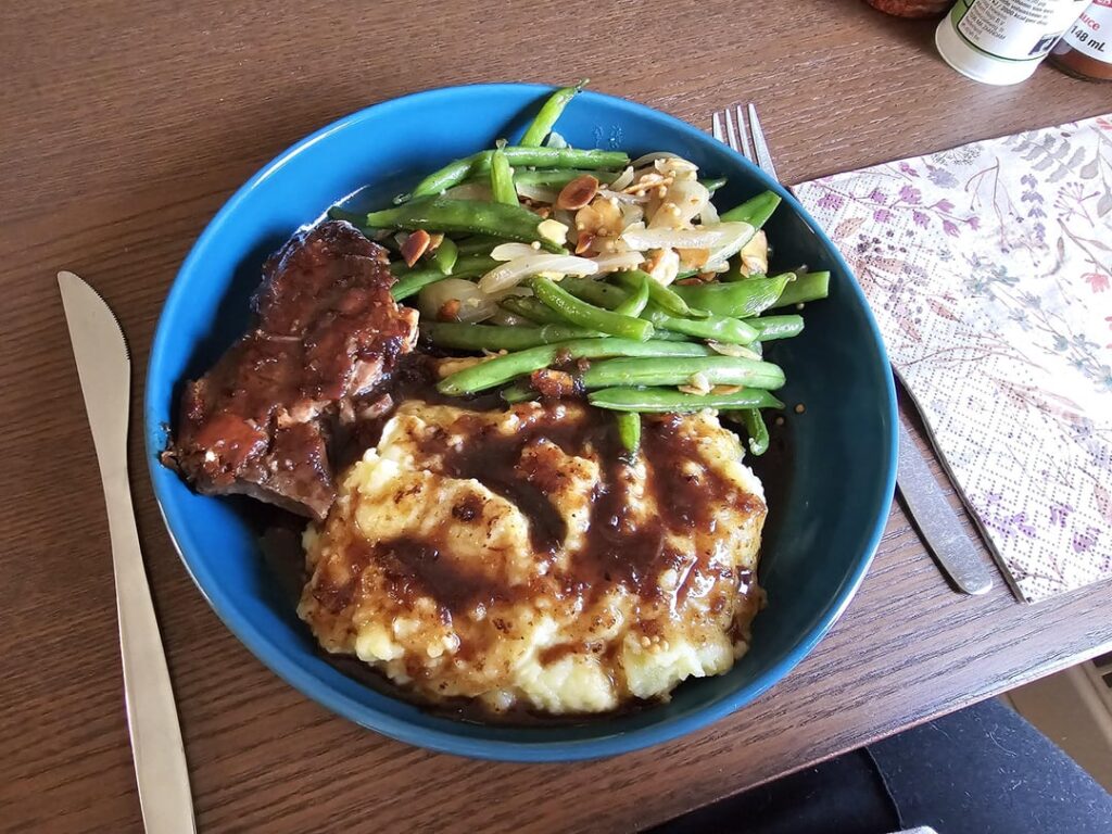 Confit duck with green beans sauteed with onions, almonds and mustard seed with garlic parmesan mash and blueberry sauce