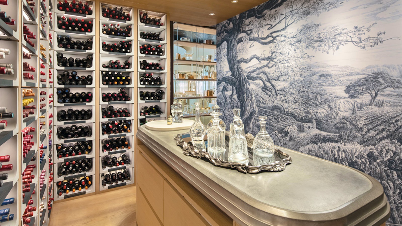 A wall of wine bottles facing a wall covered with an artwork, with a tasting table in the center of the room, at Alain Ducasse at Morpheus restaurant