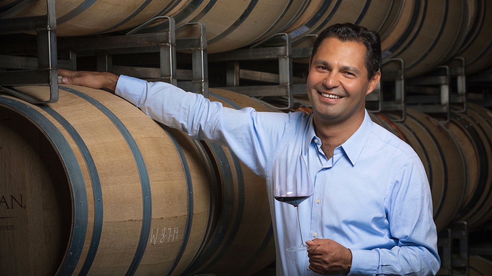 Juan Pablo Torres-Padilla holds a glass of red wine in a barrel cellar.