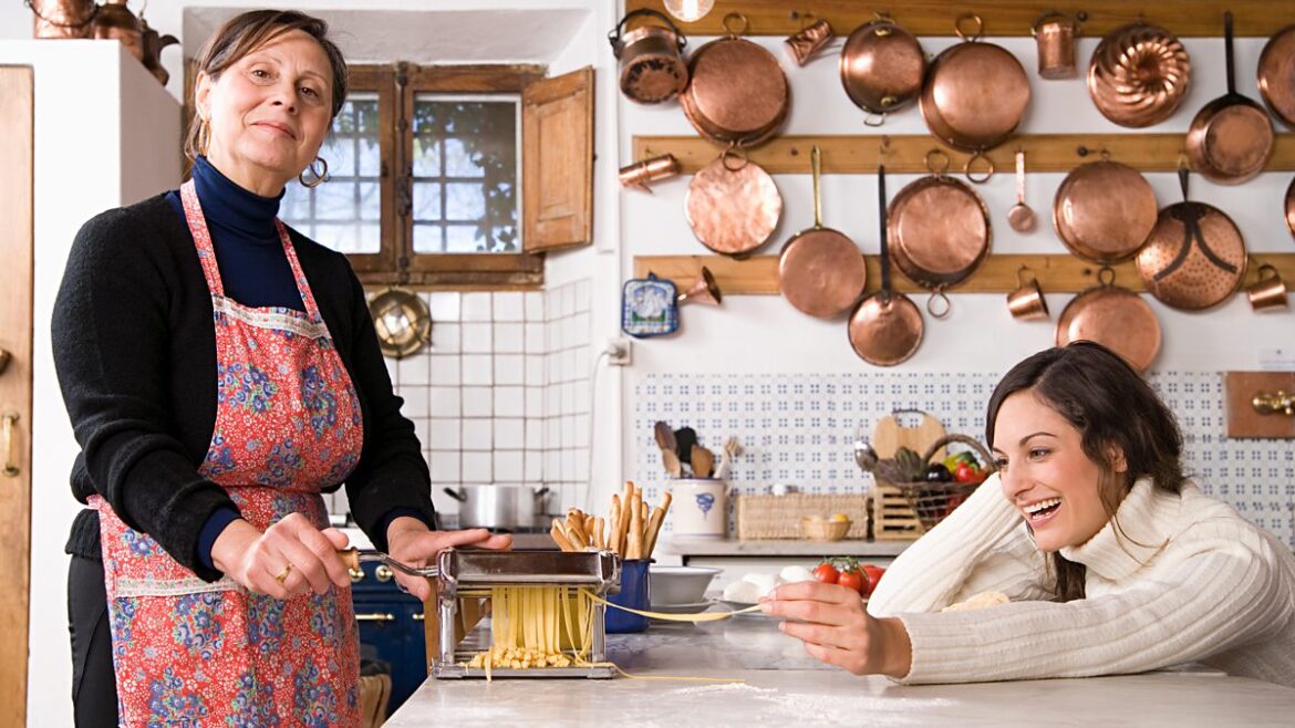 Two women stand in a kitchen in Italy making pasta