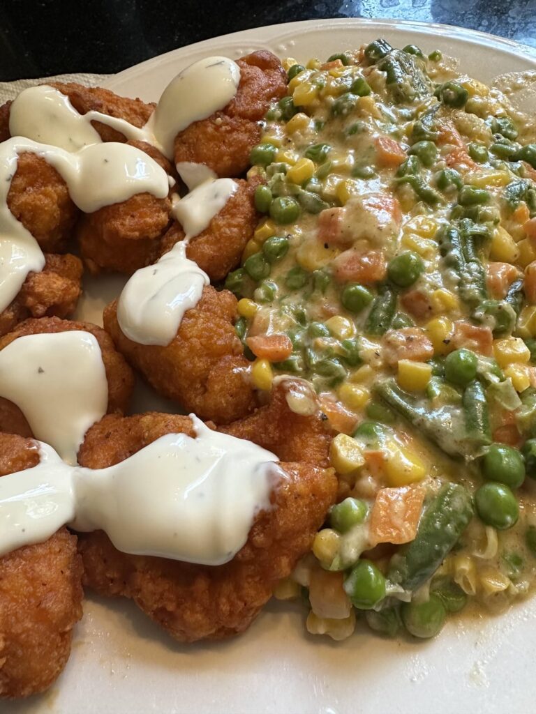 Boneless buffalo chicken bites with ranch and mixed veggies with so much Parmesan it sticks together