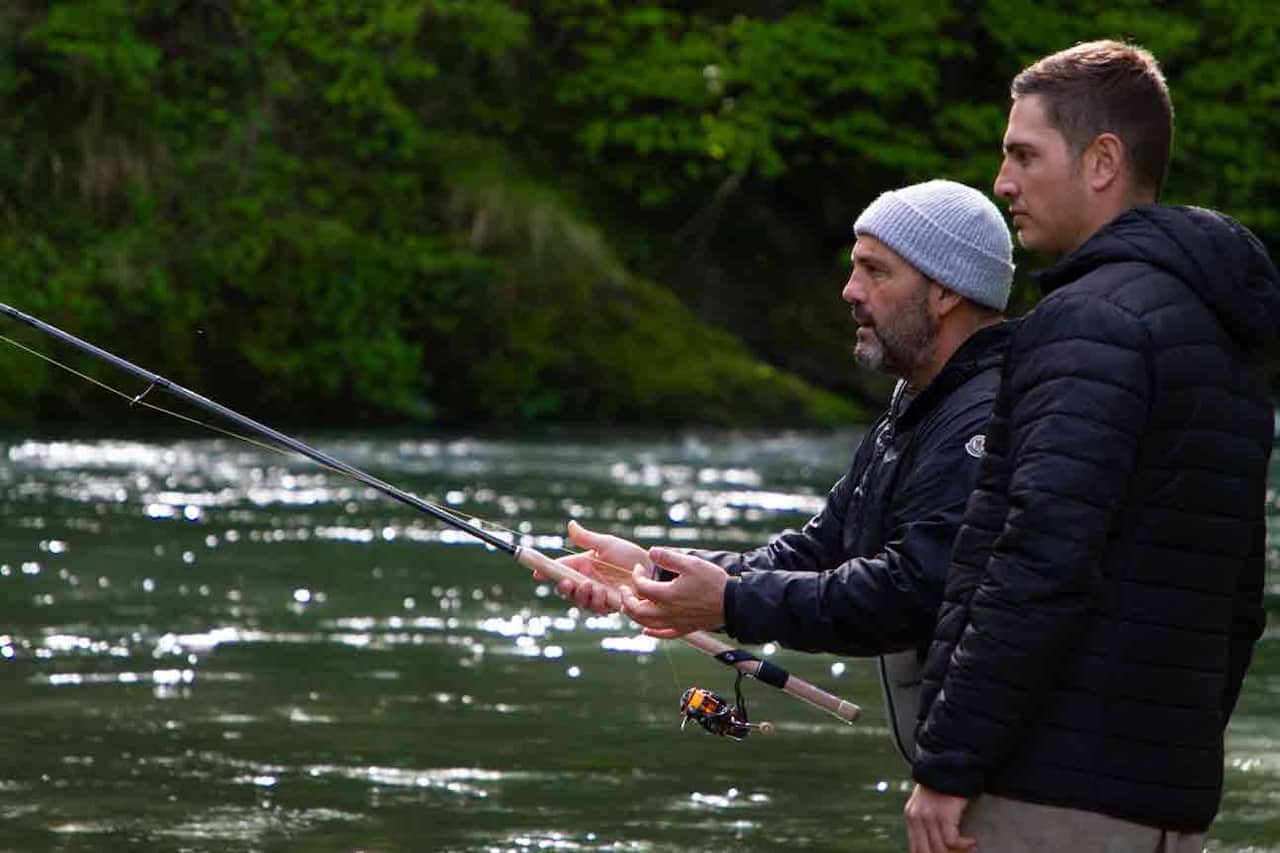 Two men stand in a river, fishing.