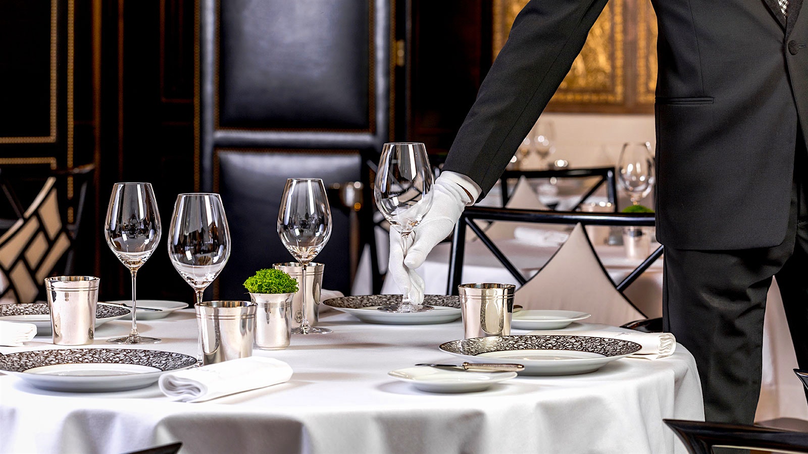 A waiter setting down wine glasses at Le Gabriel in Paris