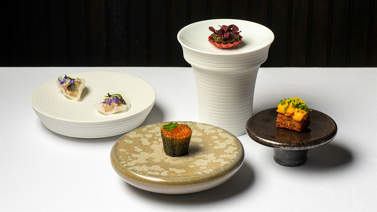 Stone plates with small dishes at Clover Hill, including a dish of uni and a dish of orange fish roe wrapped in dried seaweed