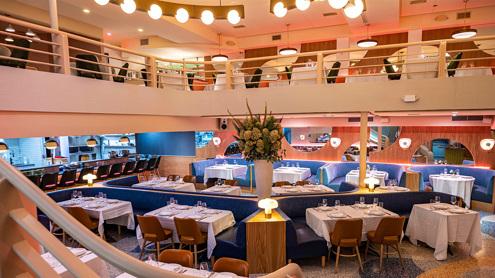 The dining room at Monterey, with blue velvet booths, spherical lighting fixtures, wood accents and bannisters and a banister reminiscent of that of a cruise ship