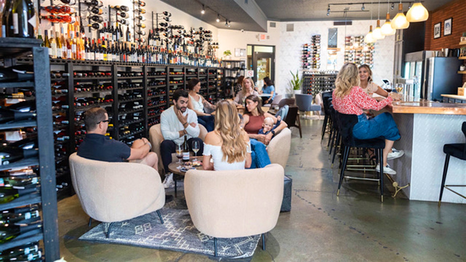 People enjoying wine at Oeno Wine Lounge near black racks of wine bottles