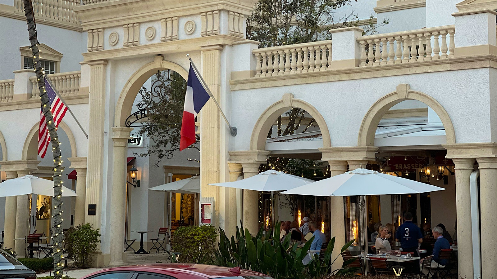 The white and beige Neoclassical-style exterior of the French Brasserie Rustique, where people are dining