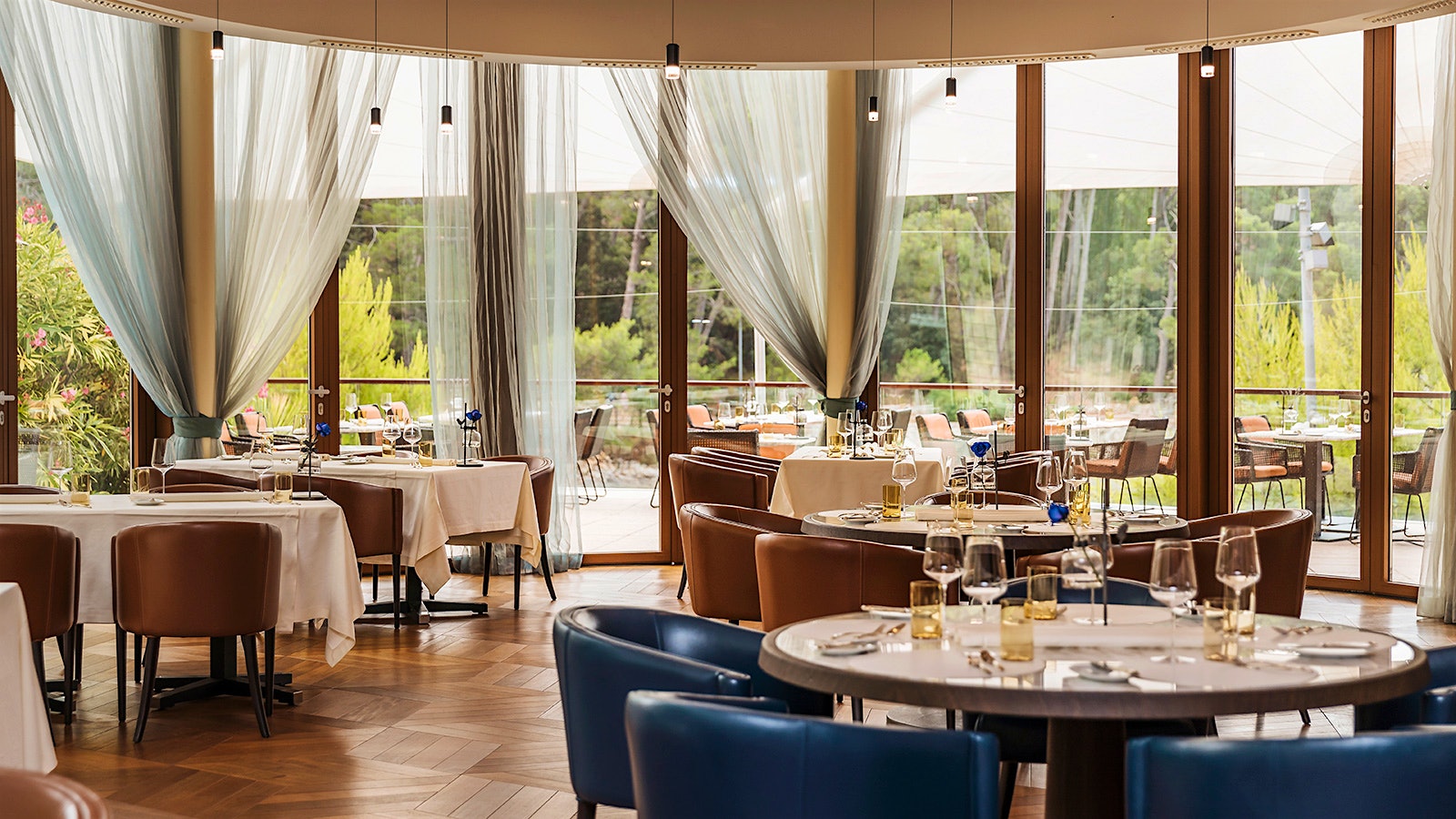  The dining room at Alfred Keller, with blue and brown leather seats, floor-to-ceiling windows and sheer curtains