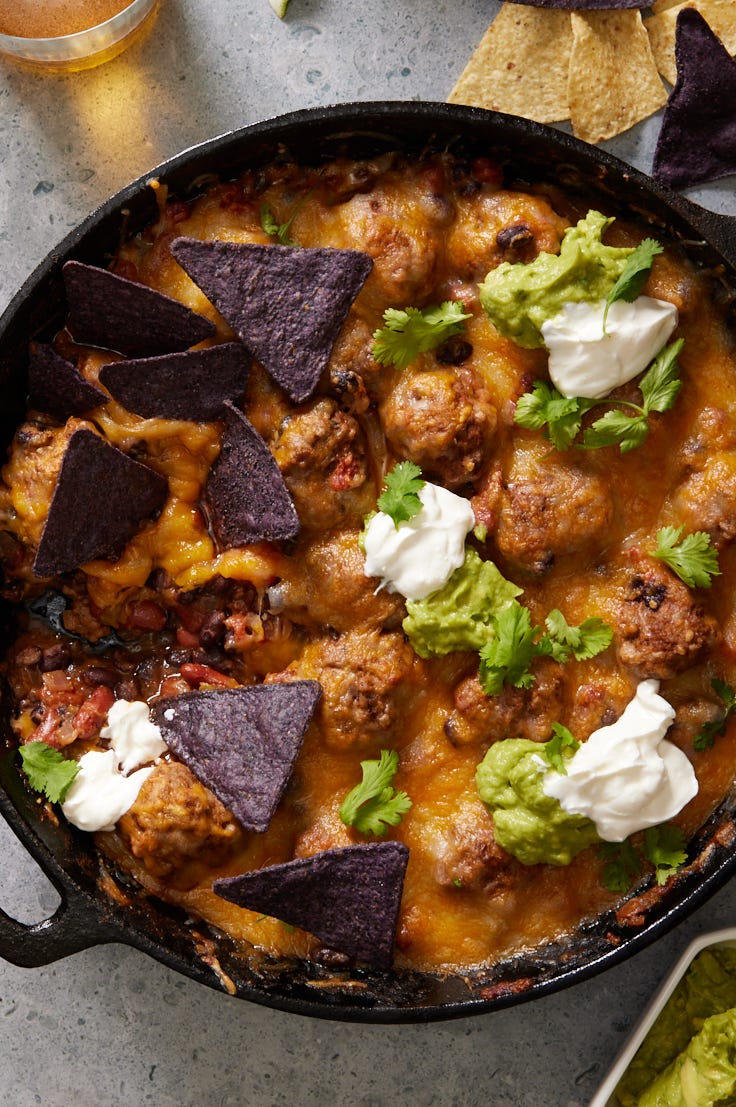 chili and meatballs in a cast iron skillet, topped with melty cheese
