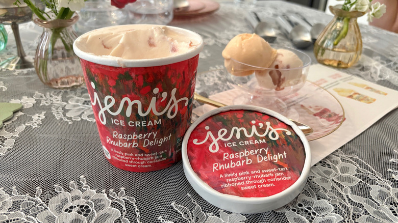 Open pint of Jeni's Raspberry Rhubarb Delight Ice Cream with dish of ice cream on a table with flowers