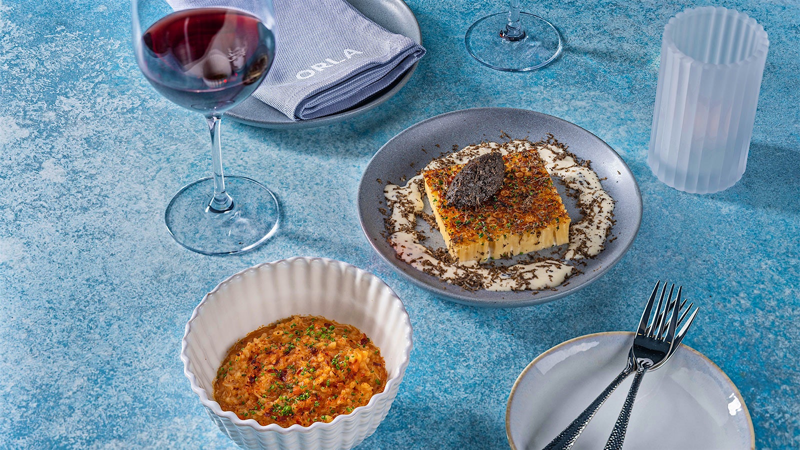  Plates with macaroni Béchamel with mushroom duxelle and crab fregula alongside a glass of red wine