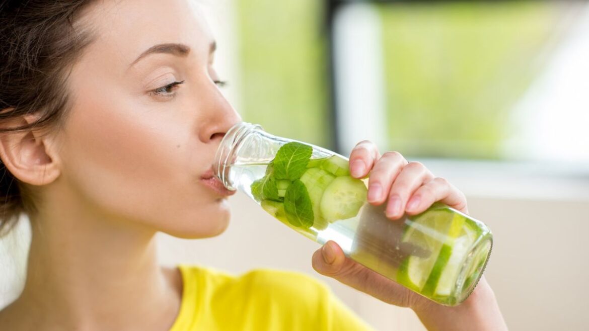 I drank cucumber water every day for two weeks — here’s what happened to my body Close up woman drinking bottle of cucumber water