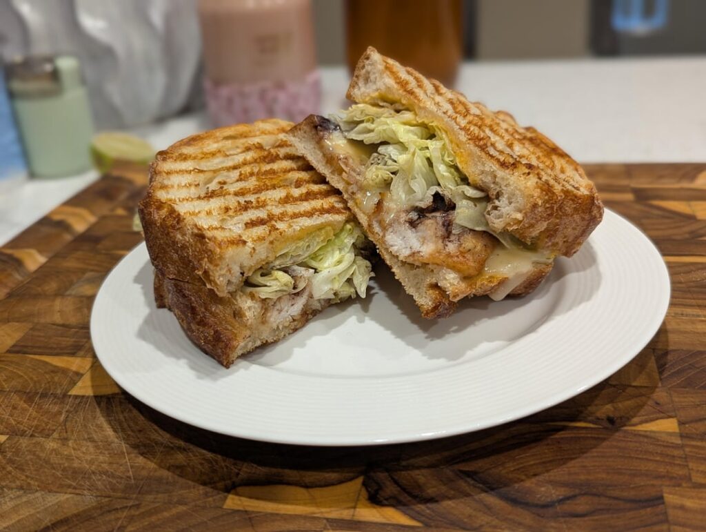 Korean style chicken breast, secret sauce, iceberg lettuce, Port Salut AOP cheese, cracked pepper, spiced grape sauce, toasted sourdough.