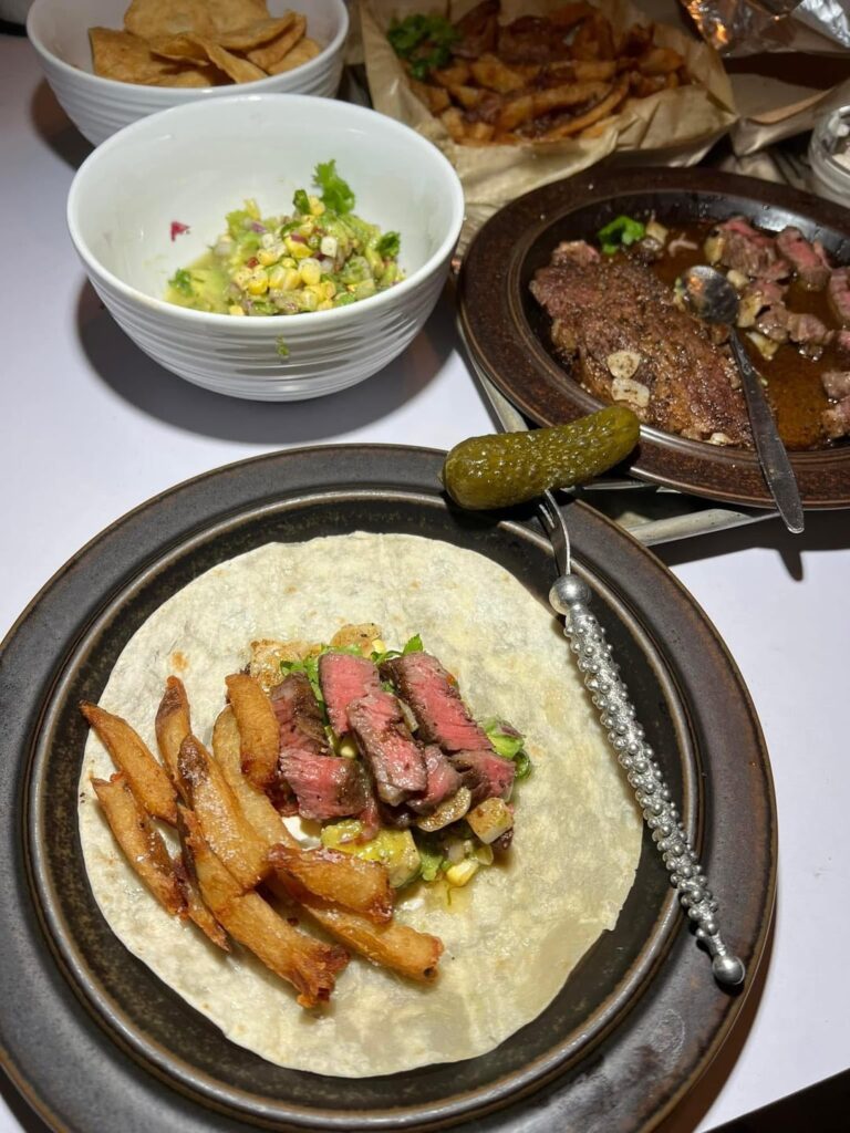 Chuck eye flour tortilla tacos with pickled corn Thai chilis guacamole, sour cream, and truffle fries