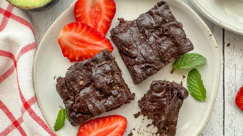 Brownies on a plate with strawberries and mint leaves