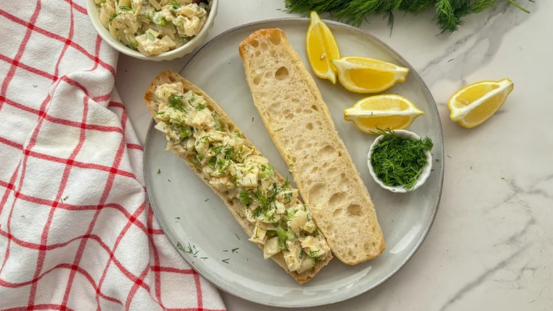 Open vegan lobster roll on plate with lemon and dill