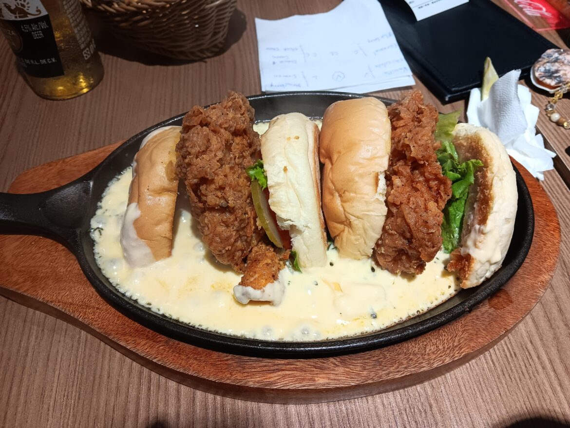 Fried chicken sandwich swimming in melted cheese